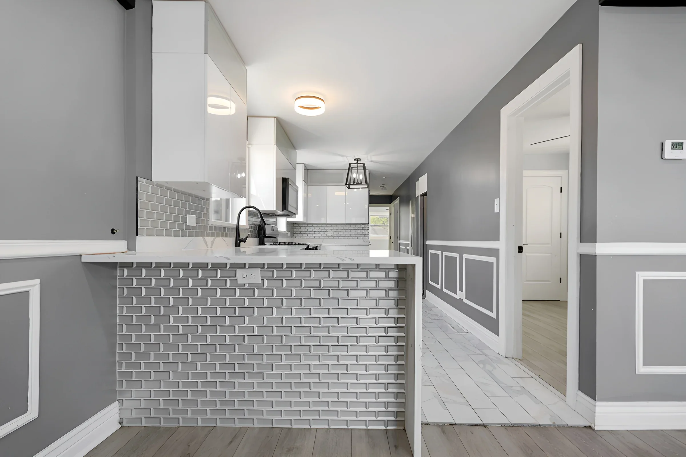 White shaker kitchen with quartz peninsula seating and brass hardware